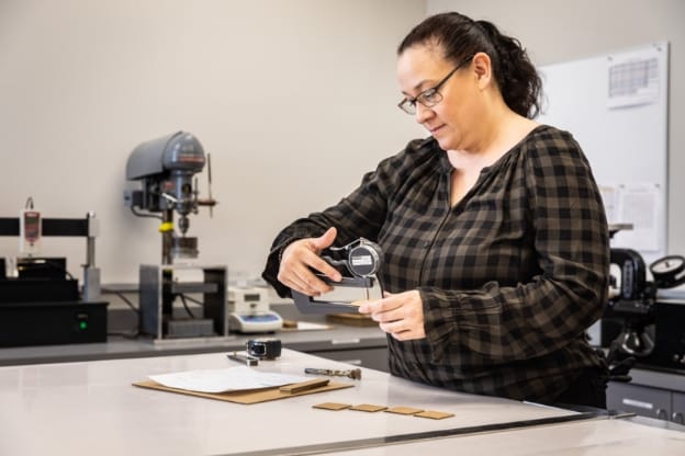 Female GBP employee testing a corrugated box’s quality in a Green Bay Packaging on-site ISTA certified lab